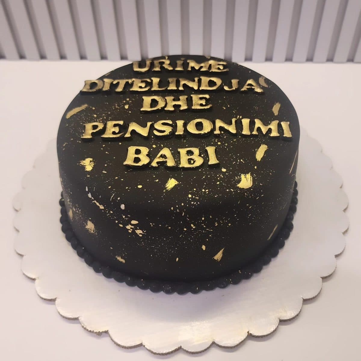 Tortë e zezë me detaje ari dhe mbishkrimin Urime ditëlindja dhe pensionimi Babi