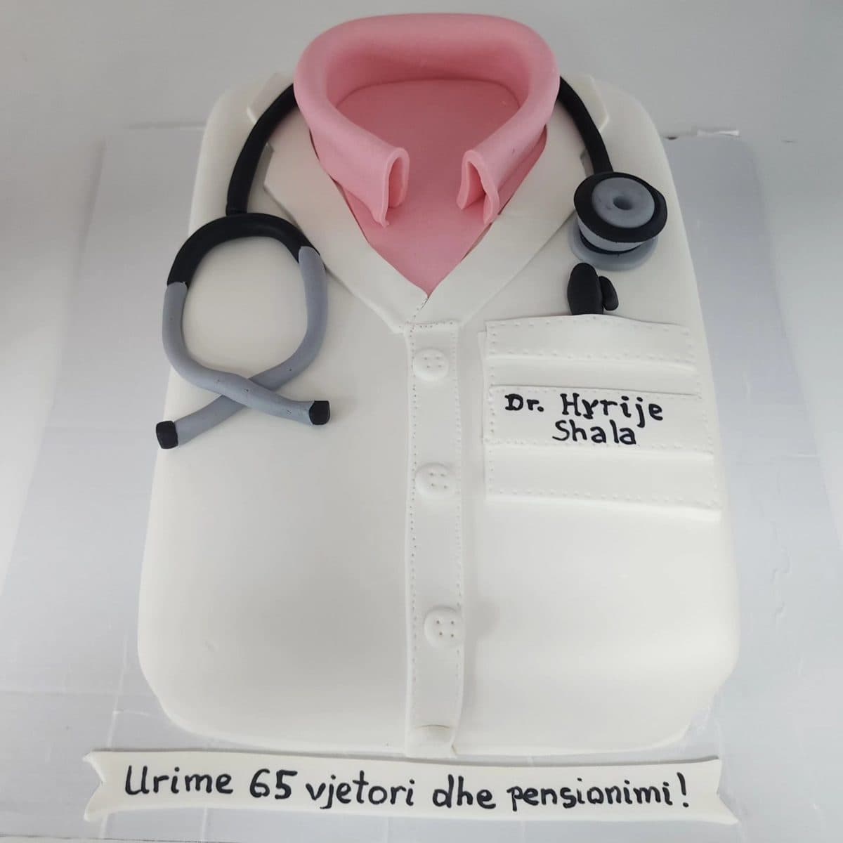 Tortë në formë uniforme mjeku me mbishkrimin Urime 65 vjetori dhe pensionimi