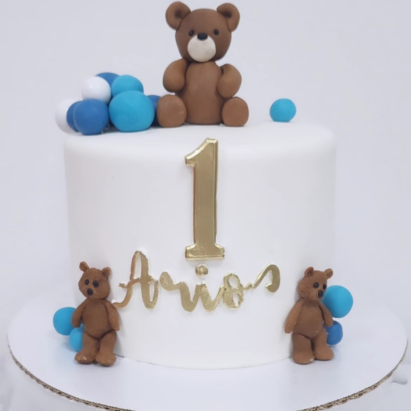 Torte e bardhë për 1-vjetor me arushë dhe dekorime blu