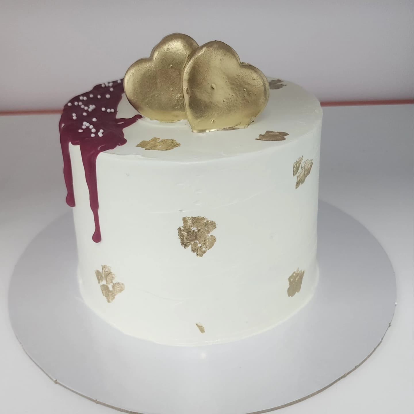 Torte e bardhë me zemra të arta dhe detaje ari