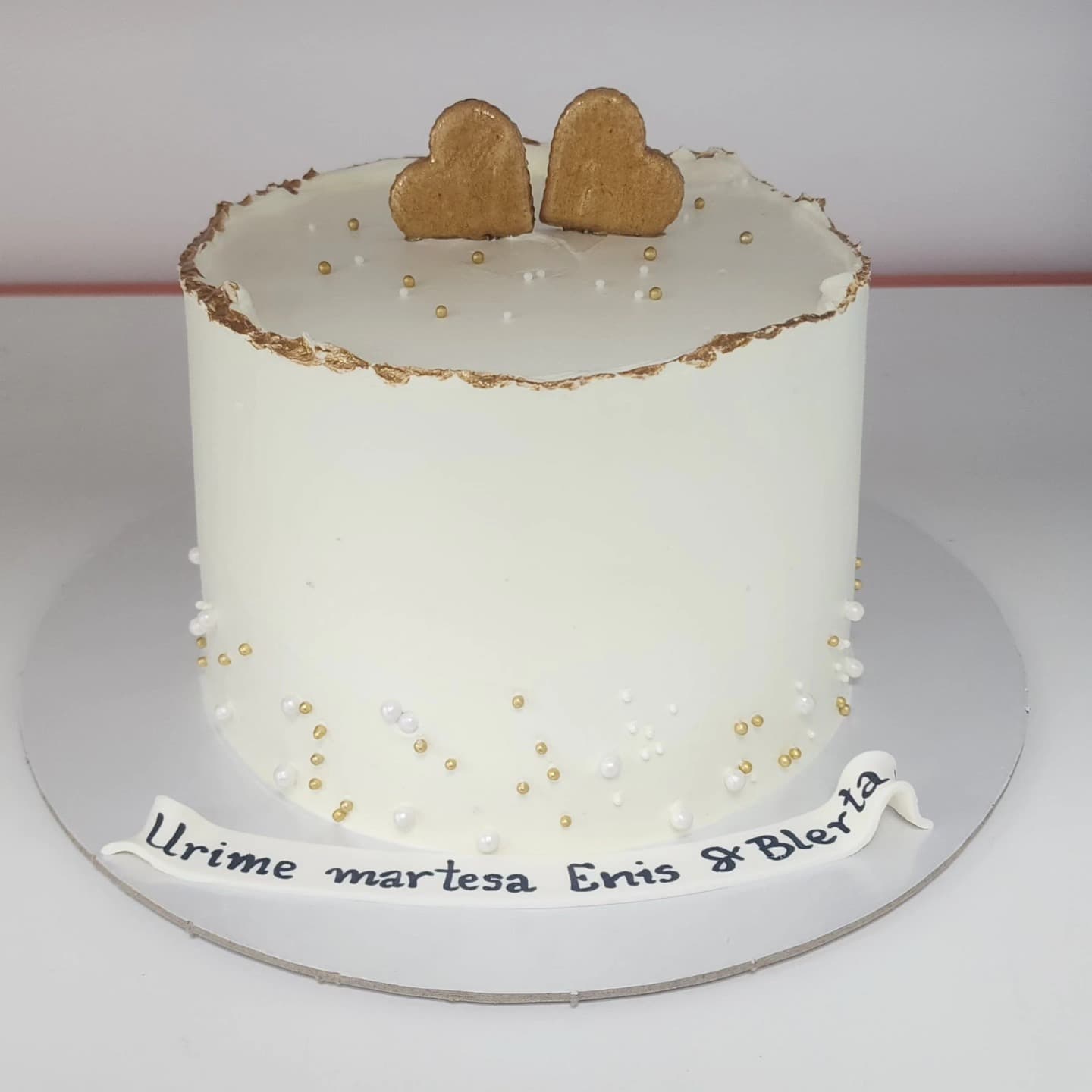 Torte martese me krem të bardhë, zbukurime me perla dhe zemra biskote