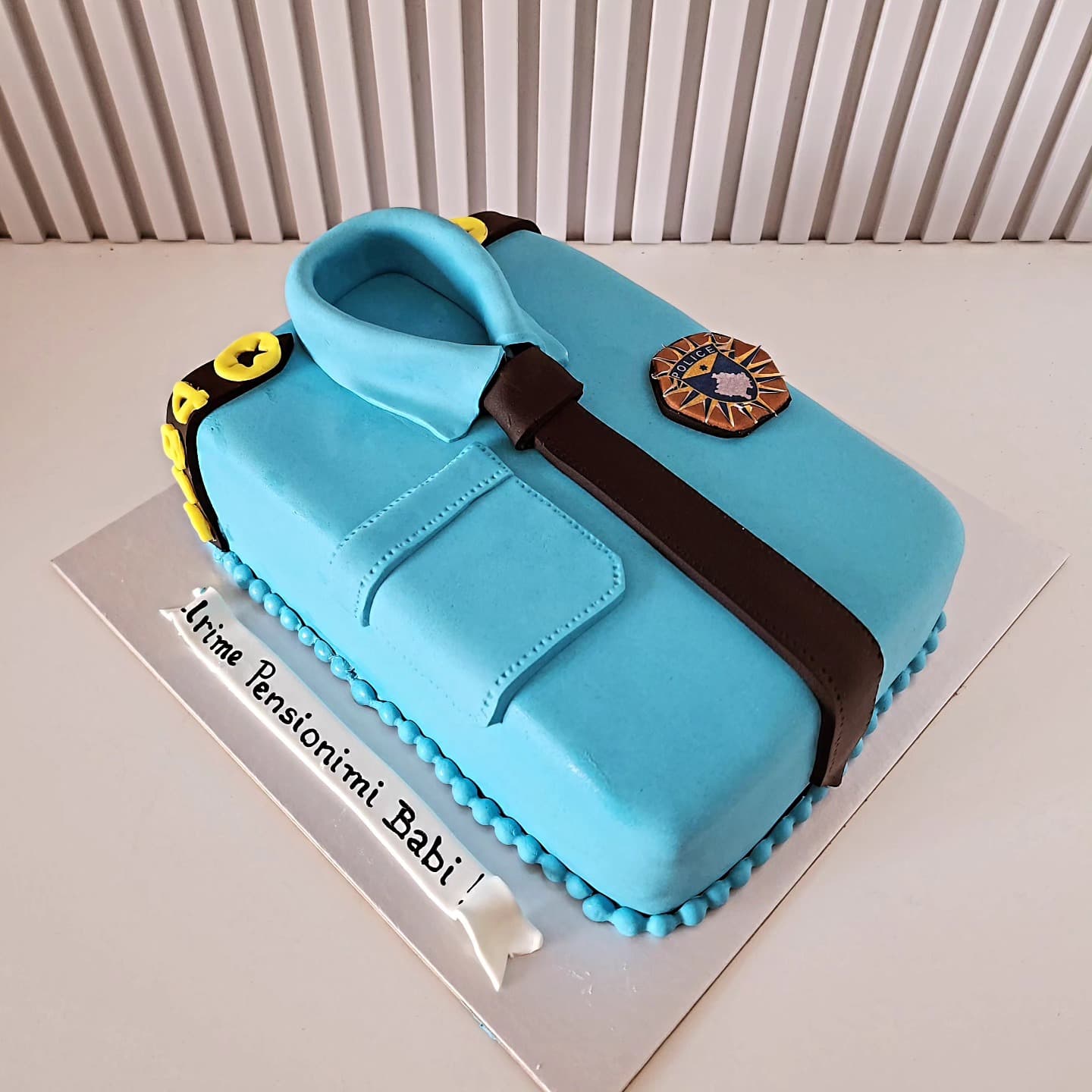 Torte e dizajnuar si uniformë policie me kravatë dhe emblemë