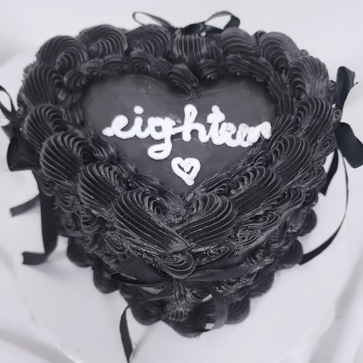 Torte e zezë në formë zemre me shkrimin eighteen