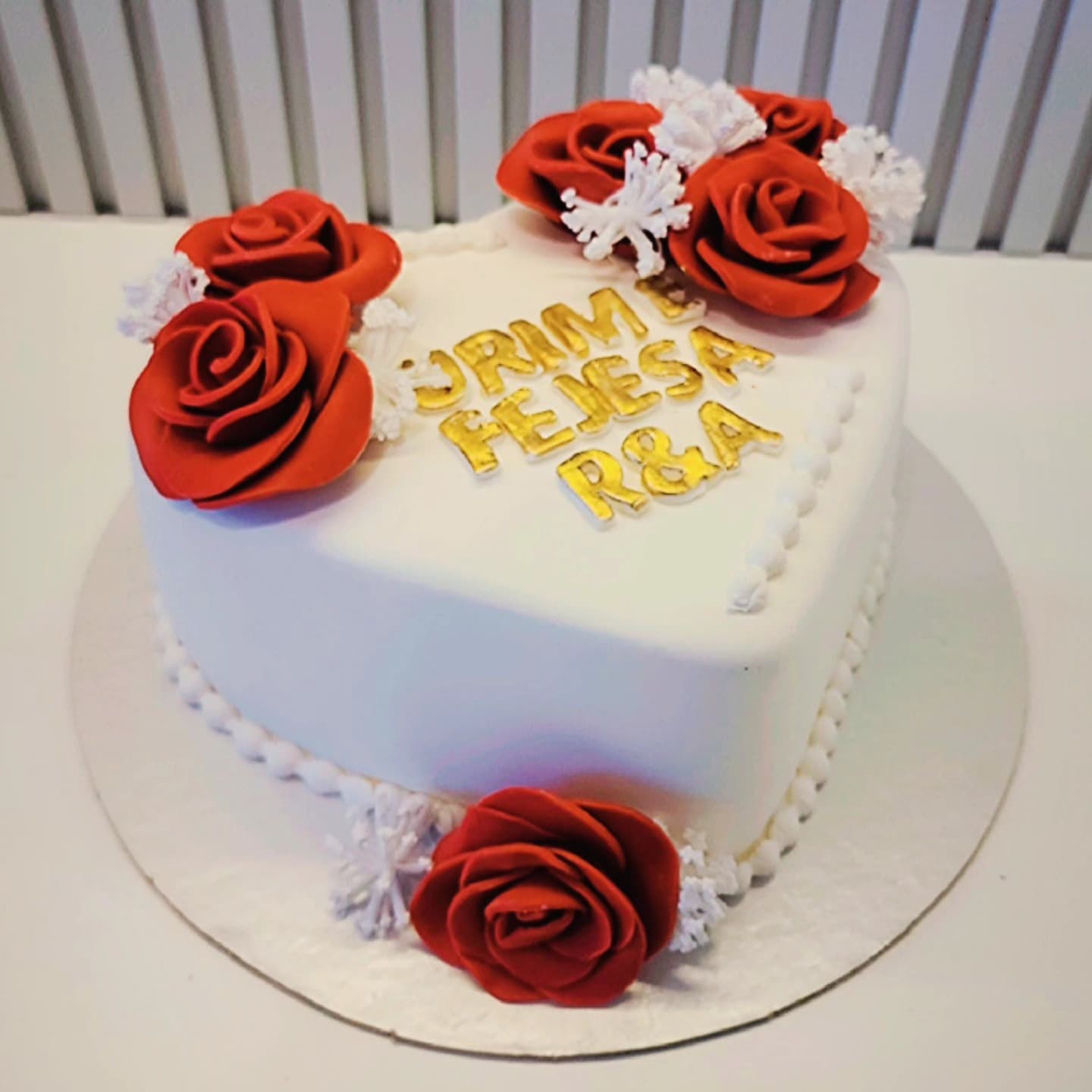 Tortë në formë zemre me trëndafila të kuq dhe zbukurime